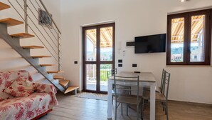 Un intérieur moderne avec un escalier, un canapé, une table à manger et un téléviseur.