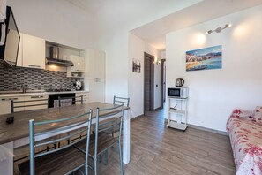 A modern kitchen with a dining area, a TV, and a bed with a floral bedspread.