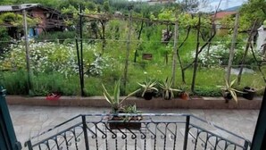 A covered outdoor area with a metal railing, potted plants, and a view of a garden and buildings in the distance. - Casa Vacanze Binellun (Sestri Levante)