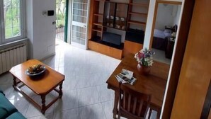 A spacious living area with a wooden dining table, a sofa, and a built-in bookshelf. - Casa Vacanze Binellun (Sestri Levante)