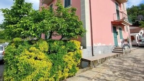 A pink building with a balcony, a tree in front, and a clear sky. - Casa Vacanze Binellun (Sestri Levante)