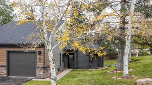 Una casa moderna con garaje, base de piedra y césped bien cuidado.