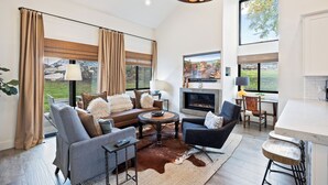 Un salón amplio con chimenea, ventanas grandes y una lámpara moderna.