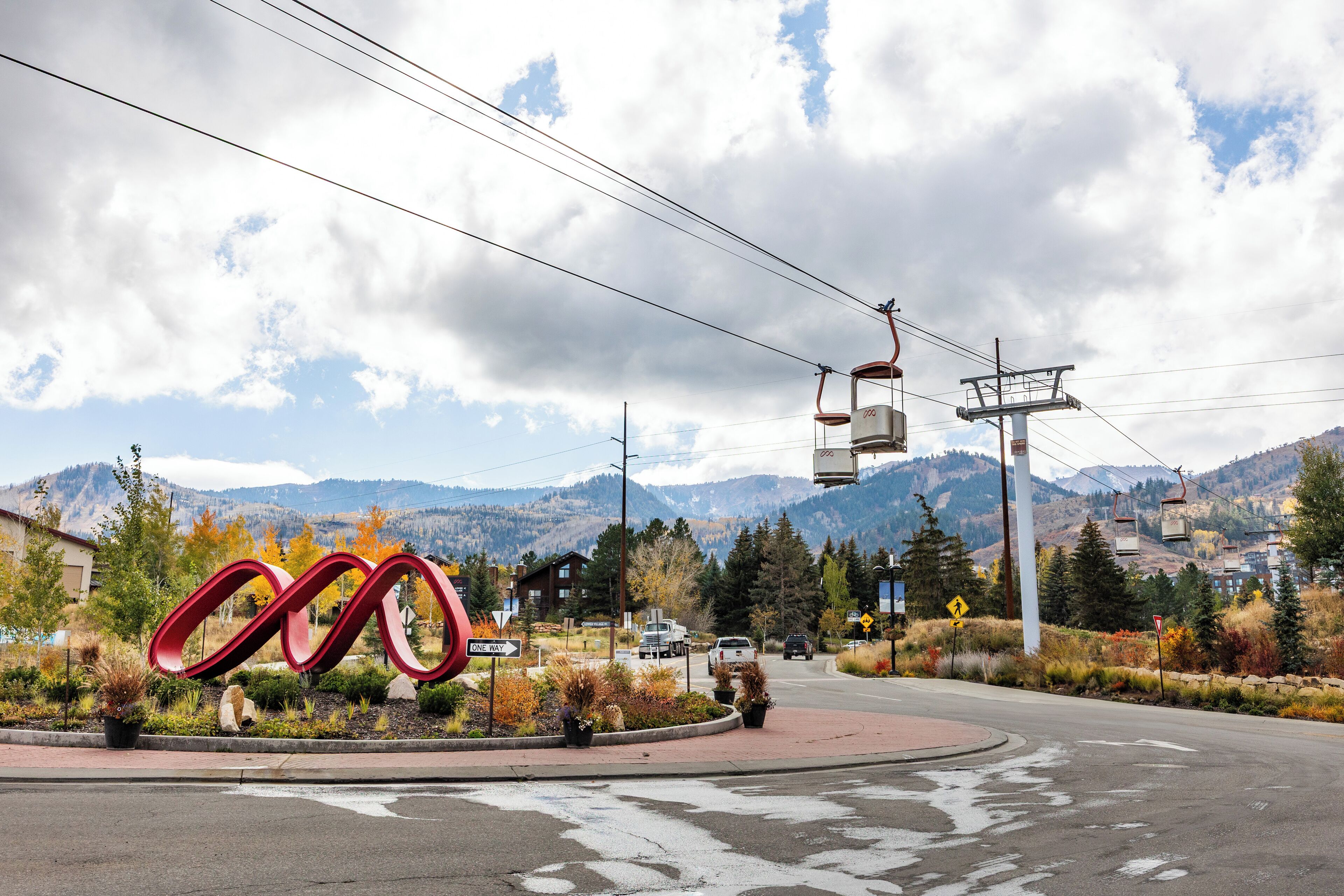 A road with a roundabout, a large red sculpture, and a mountain backdrop.