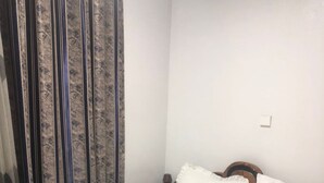 Una cama bien hecha con ropa de cama y almohadas blancas, un cabecero de madera y una cortina con estampado a rayas.