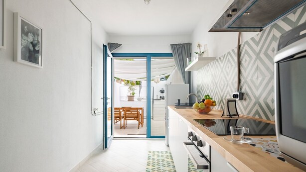 A modern kitchen with a wooden countertop, a built-in oven, and a dining area with a table and chairs. - Vacation Home "Appartamentino" with Private Terrace & Wi-Fi (Barisardo)