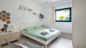 A bedroom with a bed, bedside table, lamp, and a window with a view of greenery. - Vacation Home "Appartamentino" with Private Terrace & Wi-Fi (Barisardo)