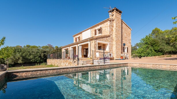 A stone building with a pool in front.