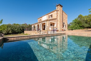 Un edificio de piedra con una piscina al frente.