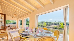A dining area with a glass table, wicker chairs, and a view of the countryside.