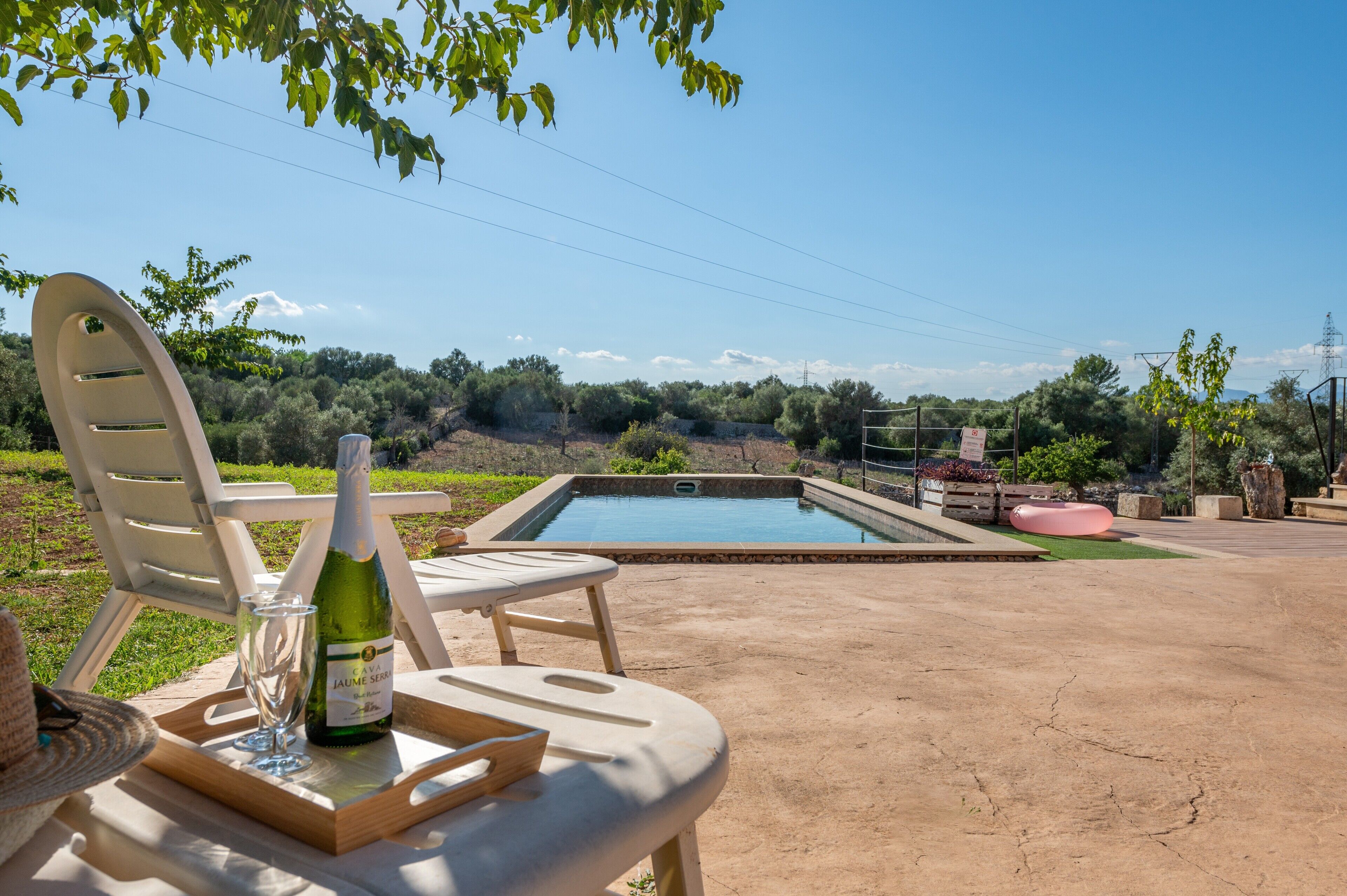 Un espace aménagé au bord de la piscine, avec une chaise, une bouteille de champagne et un verre.