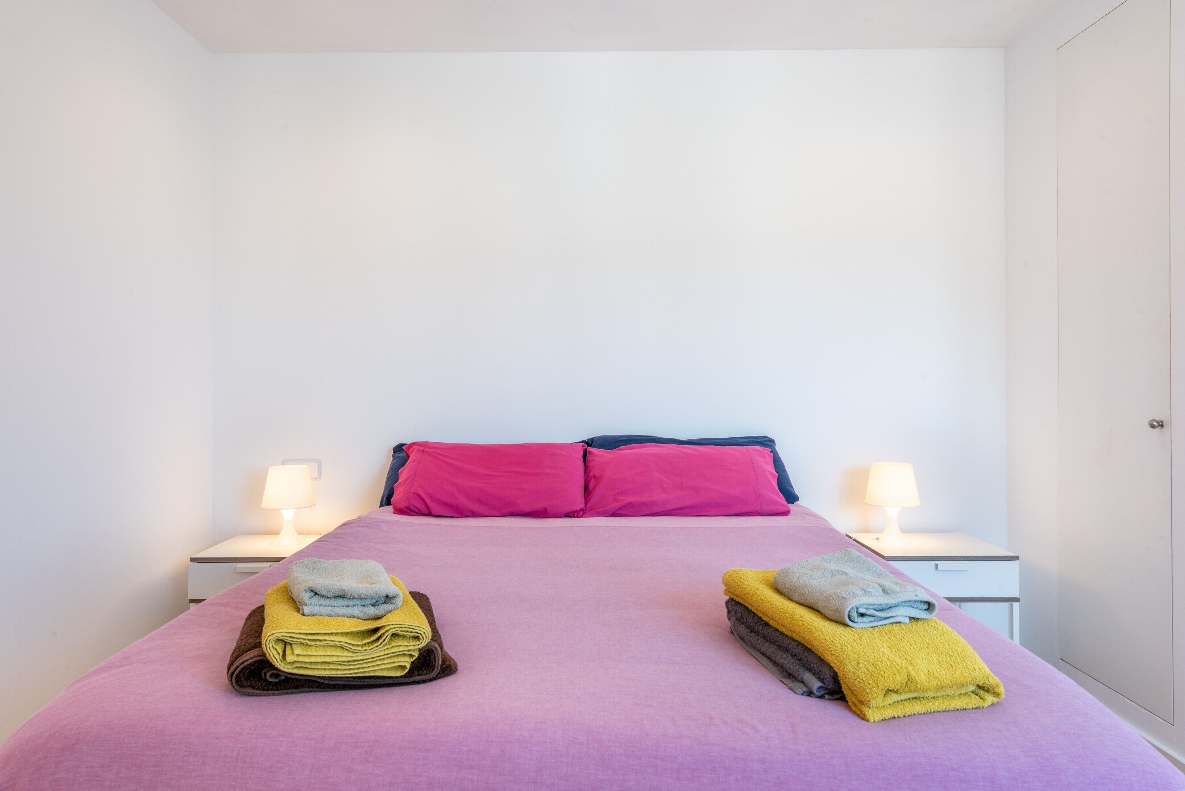 Una habitación con una cama, dos mesitas de noche y dos lámparas.