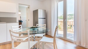Una cocina moderna con una mesa de comedor de vidrio, sillas blancas y un refrigerador de acero inoxidable.
