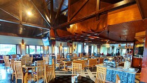 Ein großzügiger Essbereich mit Holztischen und -stühlen, einer Buffetstation und großen Fenstern mit Aussicht.