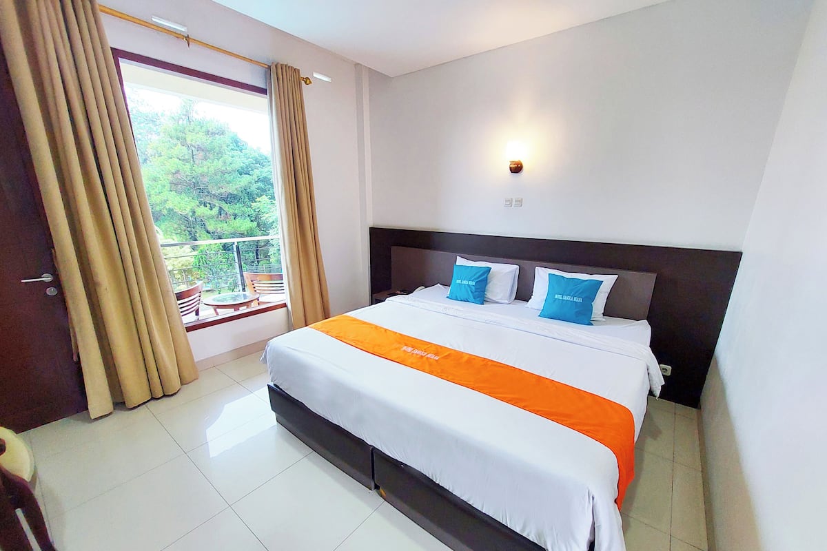 A hotel room with a large bed, a balcony with a view of greenery, and a modern design.