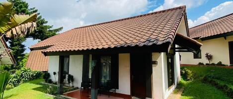 A two-story house with a tiled roof, a front porch, and a well-maintained garden.