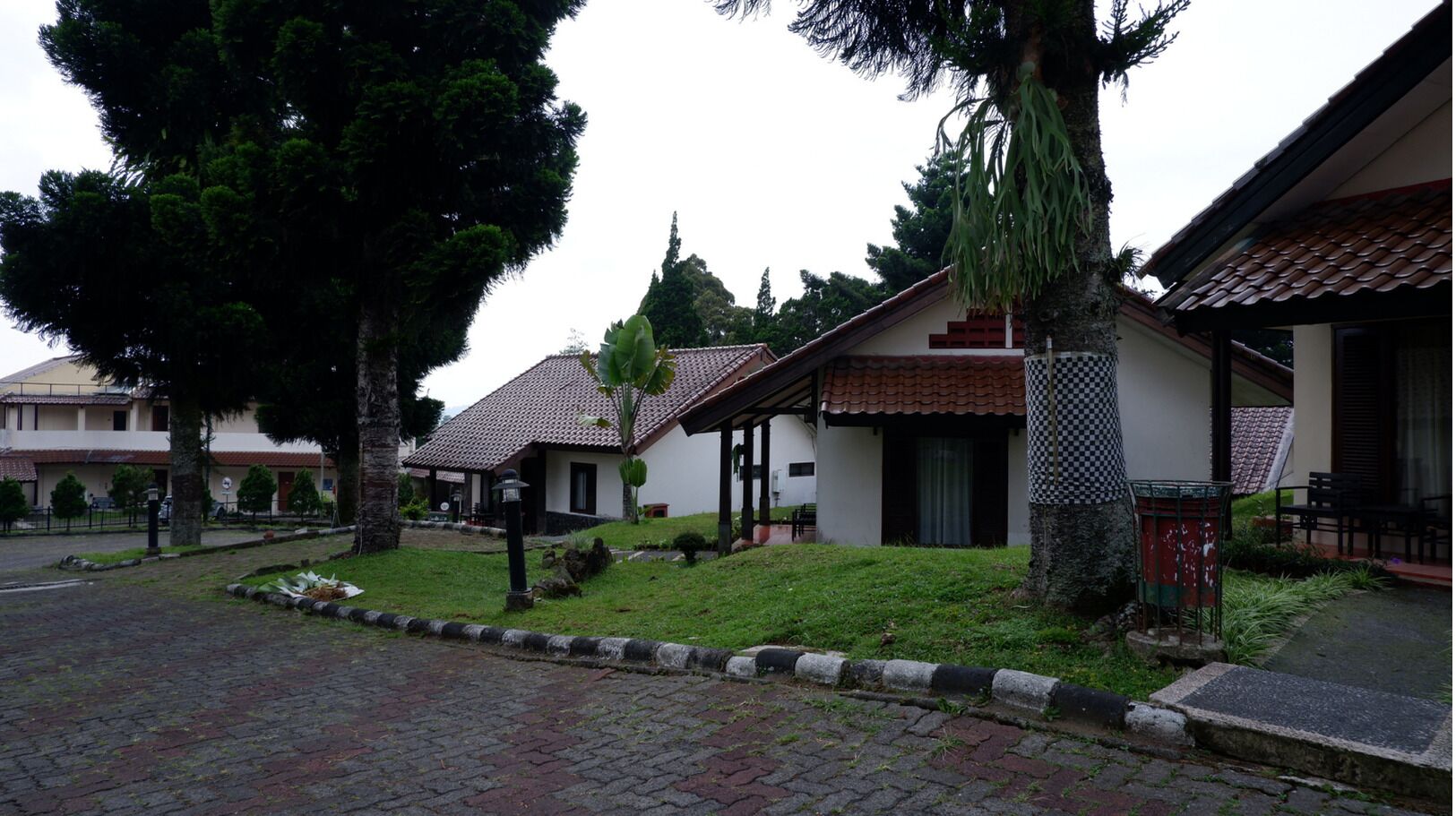 A residential area with houses featuring red-tiled roofs, a paved driveway, and a well-maintained lawn.