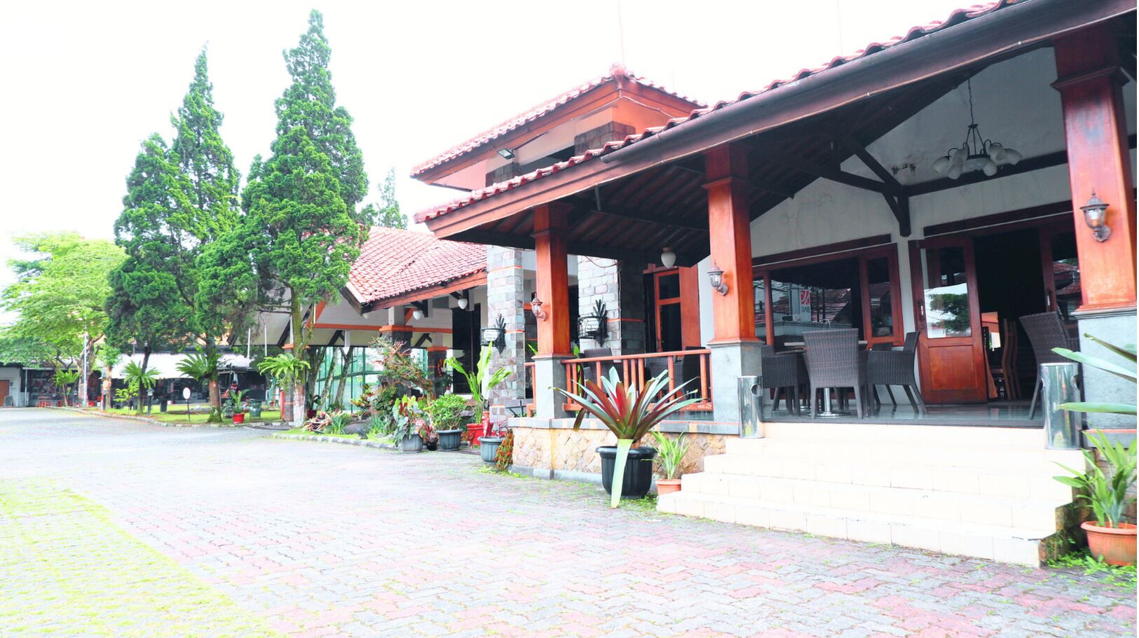A traditional building with a covered entrance, potted plants, and outdoor seating.