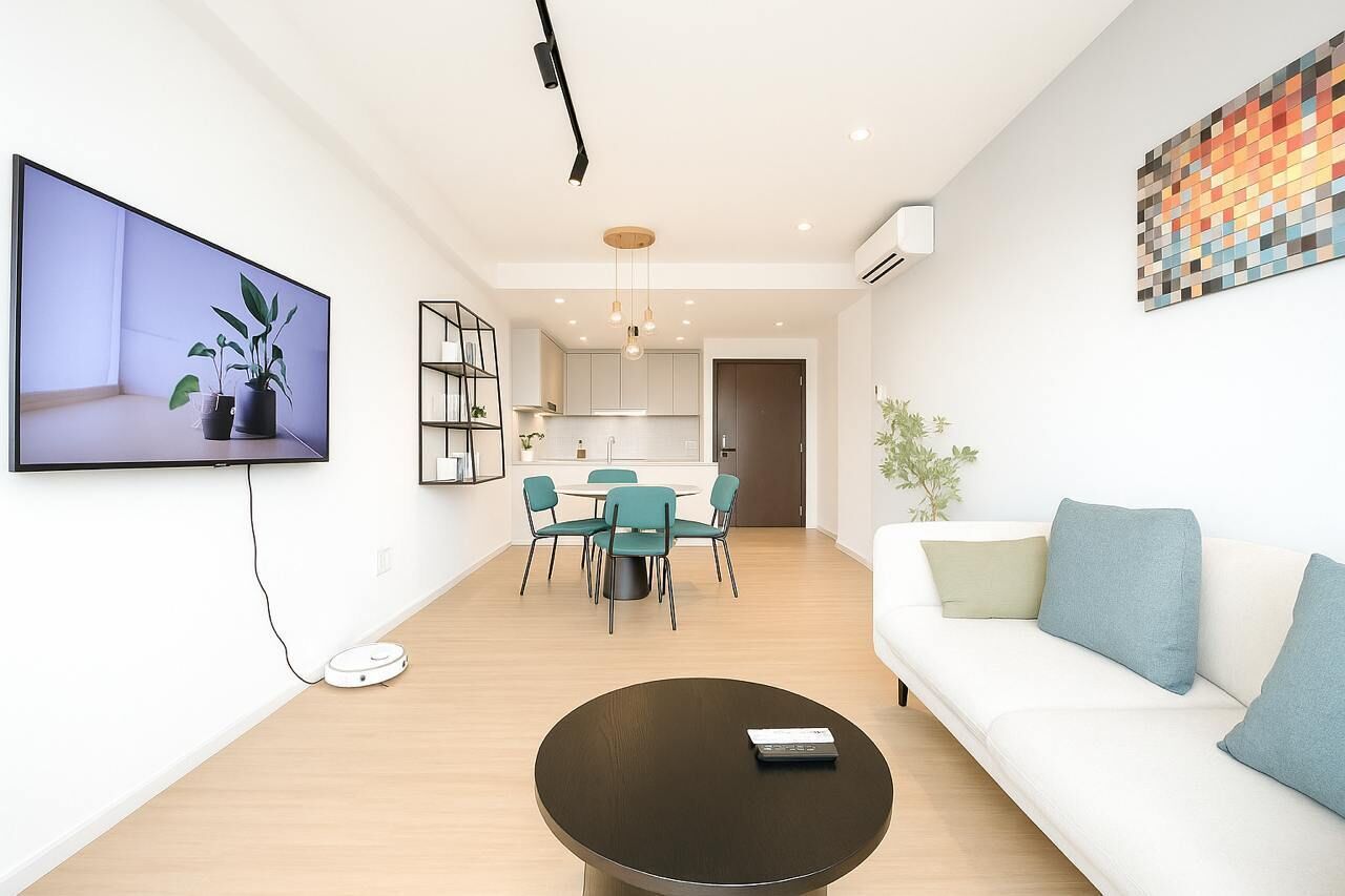 En moderne stue med et fladskærms-tv, et sofabord, en sofa og et spiseområde med stole og et bord.