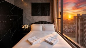 Une chambre d’hôtel moderne avec un grand lit, une vue sur la ville et un mur en marbre.