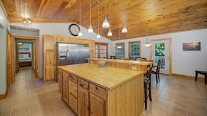 Una cocina amplia con armarios de madera, una isla central e iluminación colgante.