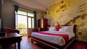 A hotel room with a large bed, a wooden nightstand, a desk, and a view of the outdoors through a window. - Hotel Parv (Jaipur)