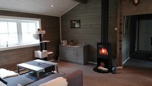 A cozy living room with a fireplace, a cat tree, and a sofa. - Cozy Cabin Near Trysil (Innlandet)