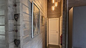 A hallway with wooden paneling, a white door, and a fire extinguisher on the wall. - Cozy Cabin Near Trysil (Innlandet)