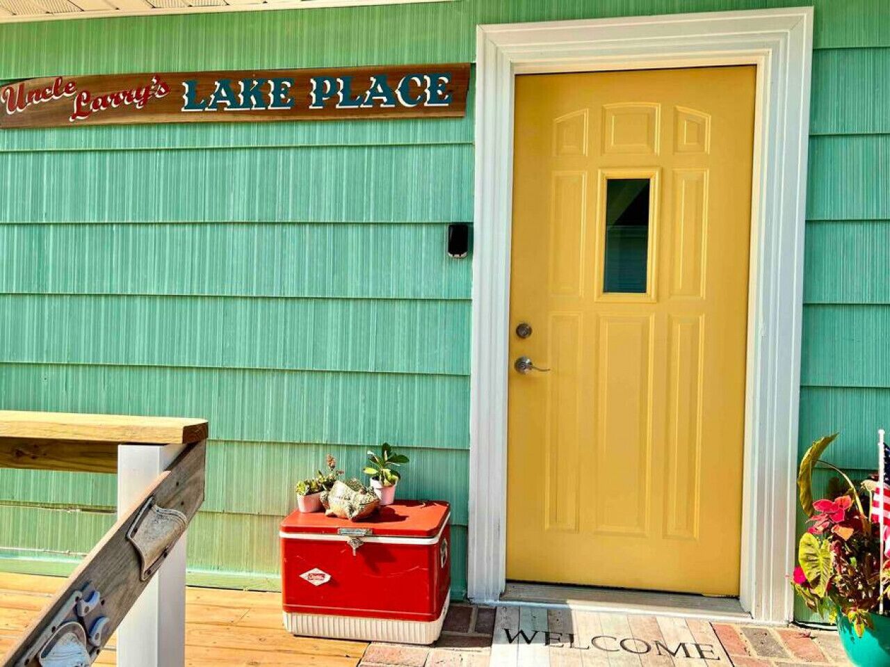Un edificio con fachada verde, una puerta amarilla y un letrero que dice "Uncle Larry's Lake Place".