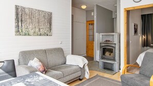 Una sala de estar moderna con un sofá gris, una chimenea y un cuadro abstracto grande en la pared.