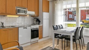Una cocina moderna con armarios de madera, una estufa blanca y un comedor con mesa y sillas.