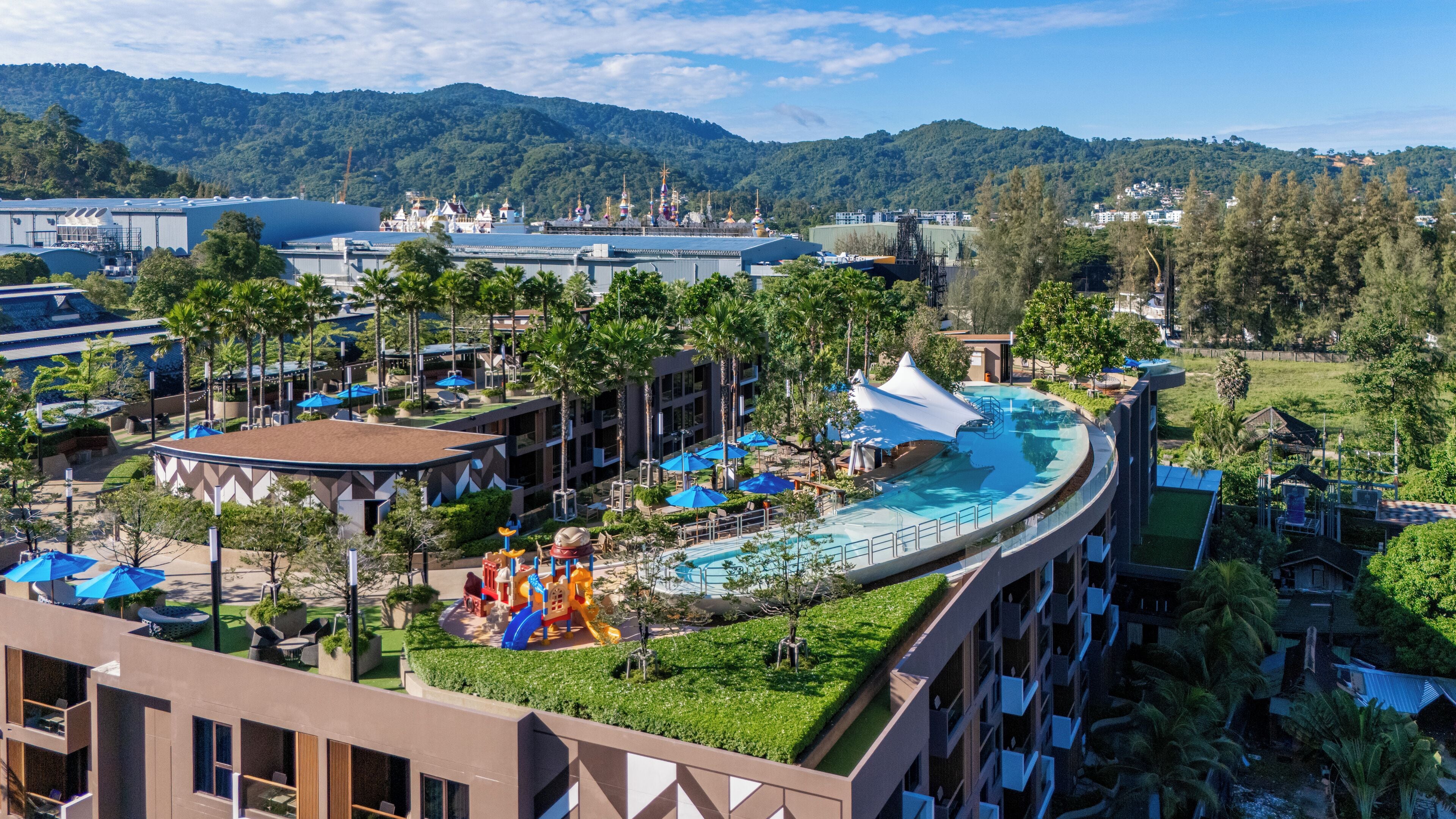 A resort with a pool, a playground, and a view of the mountains.