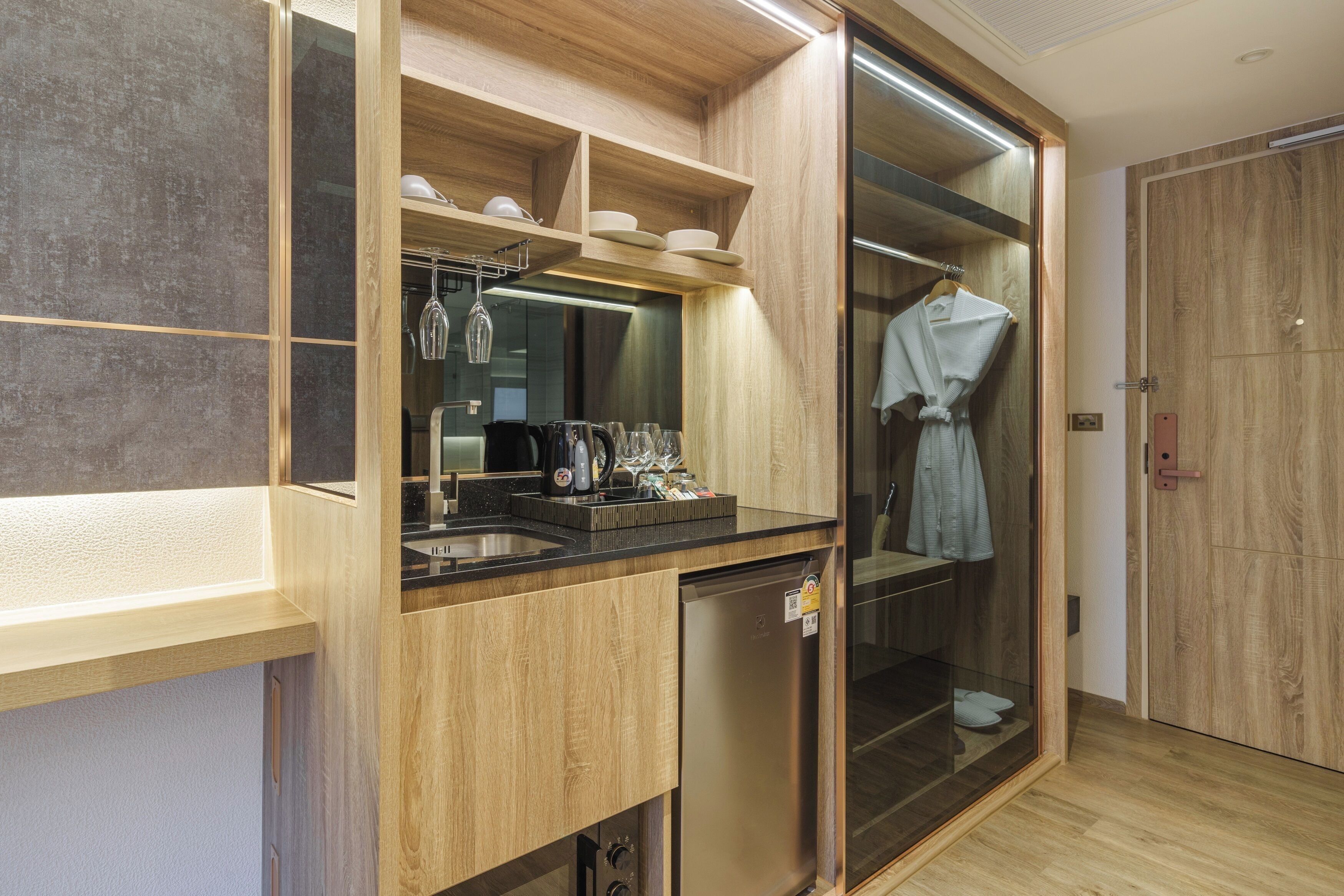Una cocina moderna con armarios de madera, lavavajillas integrado y una despensa con puerta de vidrio.