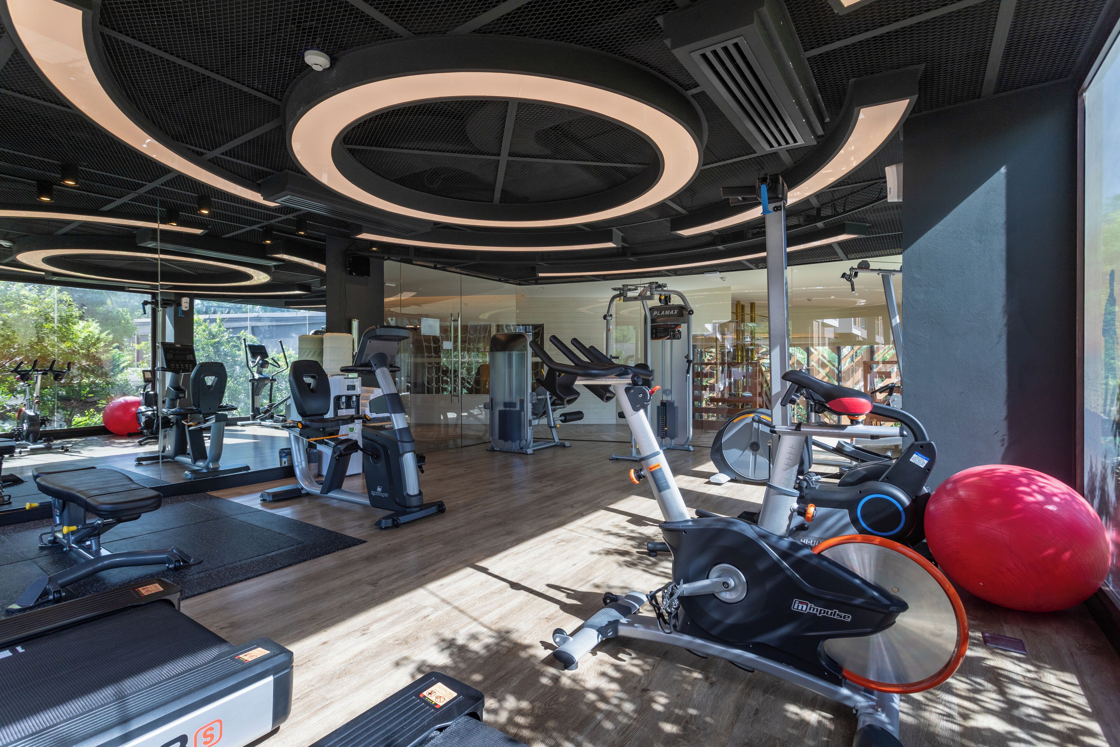 Une salle de sport moderne équipée de divers appareils d’exercice, notamment des tapis de course, des vélos d’appartement et des poids libres.