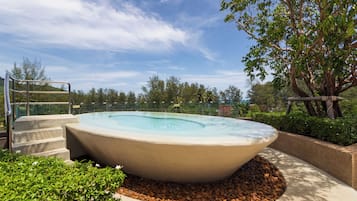 Un bain à remous entouré d’une bordure en pierre, avec des marches menant à l’intérieur.