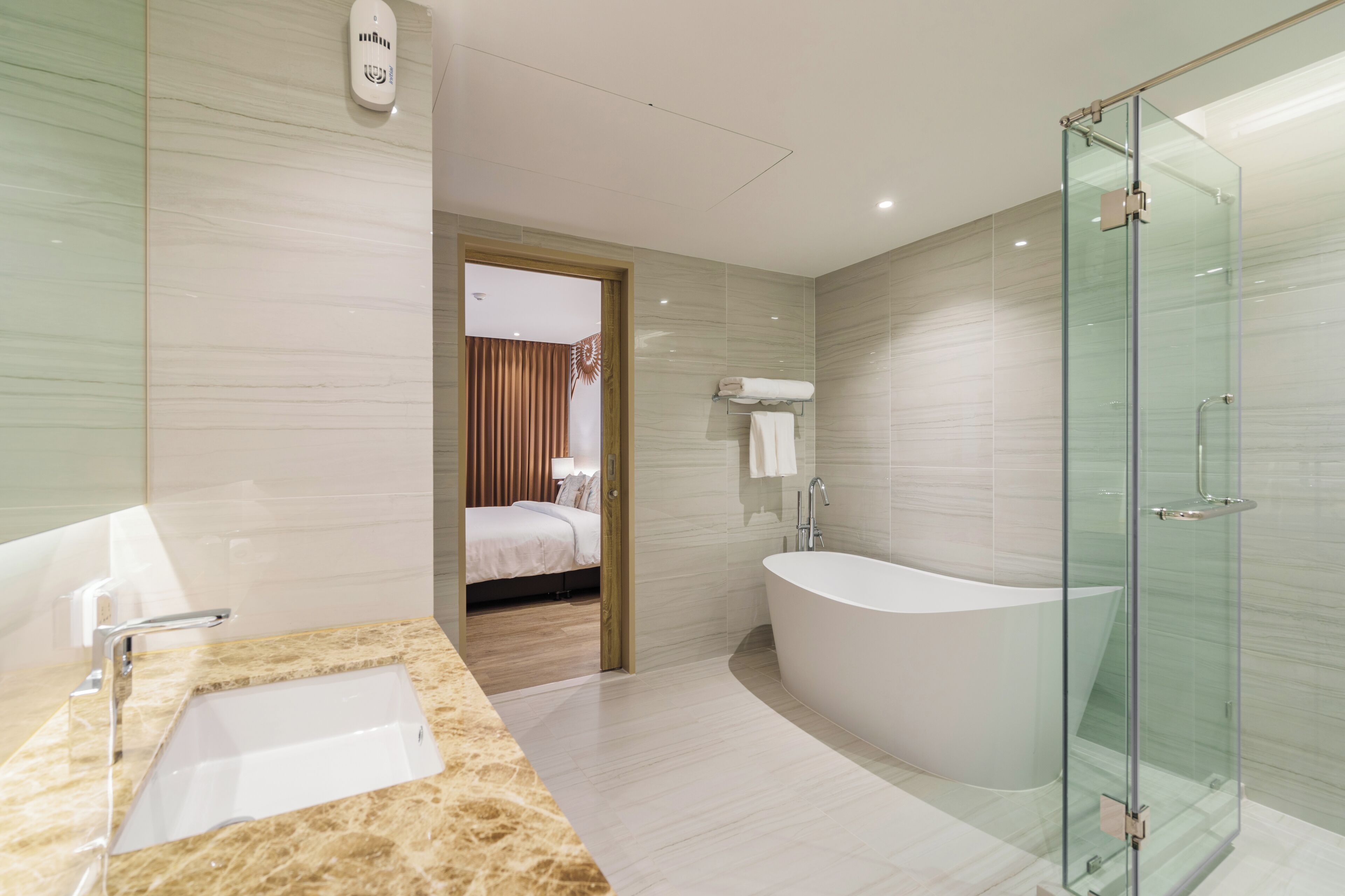 A modern bathroom with a glass-enclosed shower, a freestanding bathtub, and a marble sink.