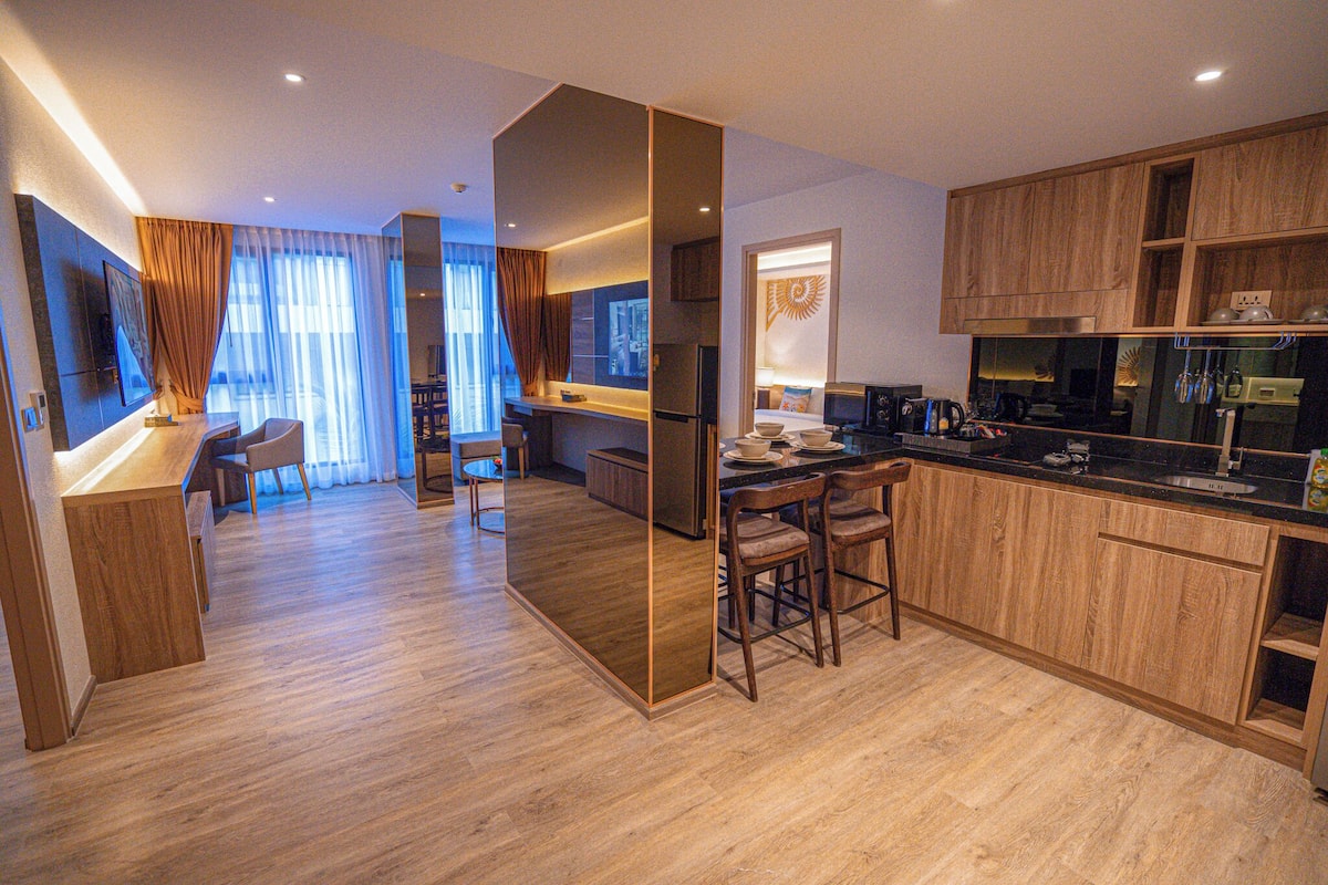 A modern kitchen with wooden cabinets, a dining area with a table and chairs, and a large window with curtains.