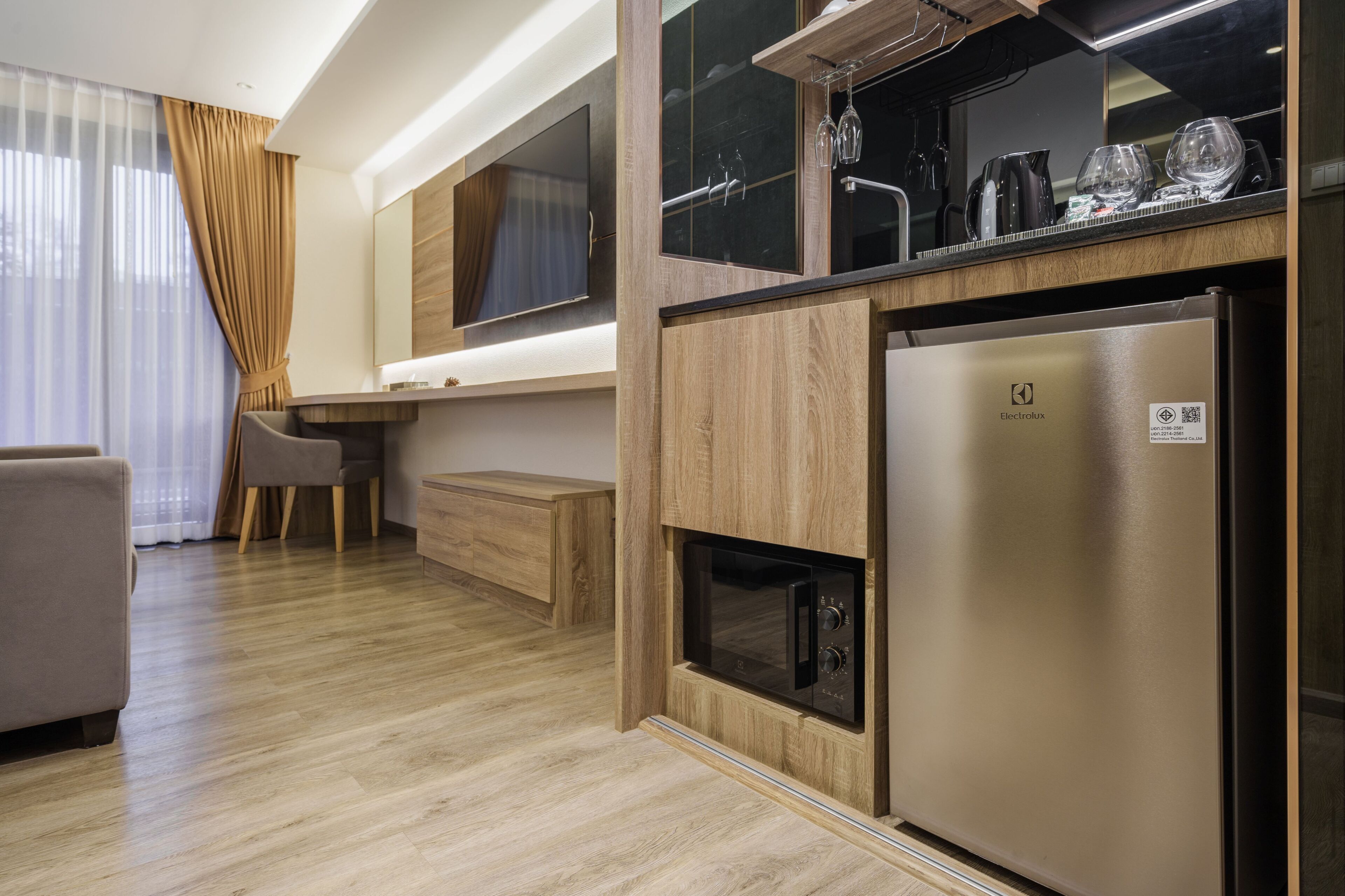 A modern kitchen with a built-in microwave, a stainless steel refrigerator, and a wooden countertop.