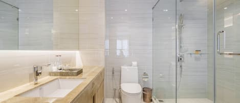 A modern bathroom with a glass-enclosed shower, a large sink, and a toilet.