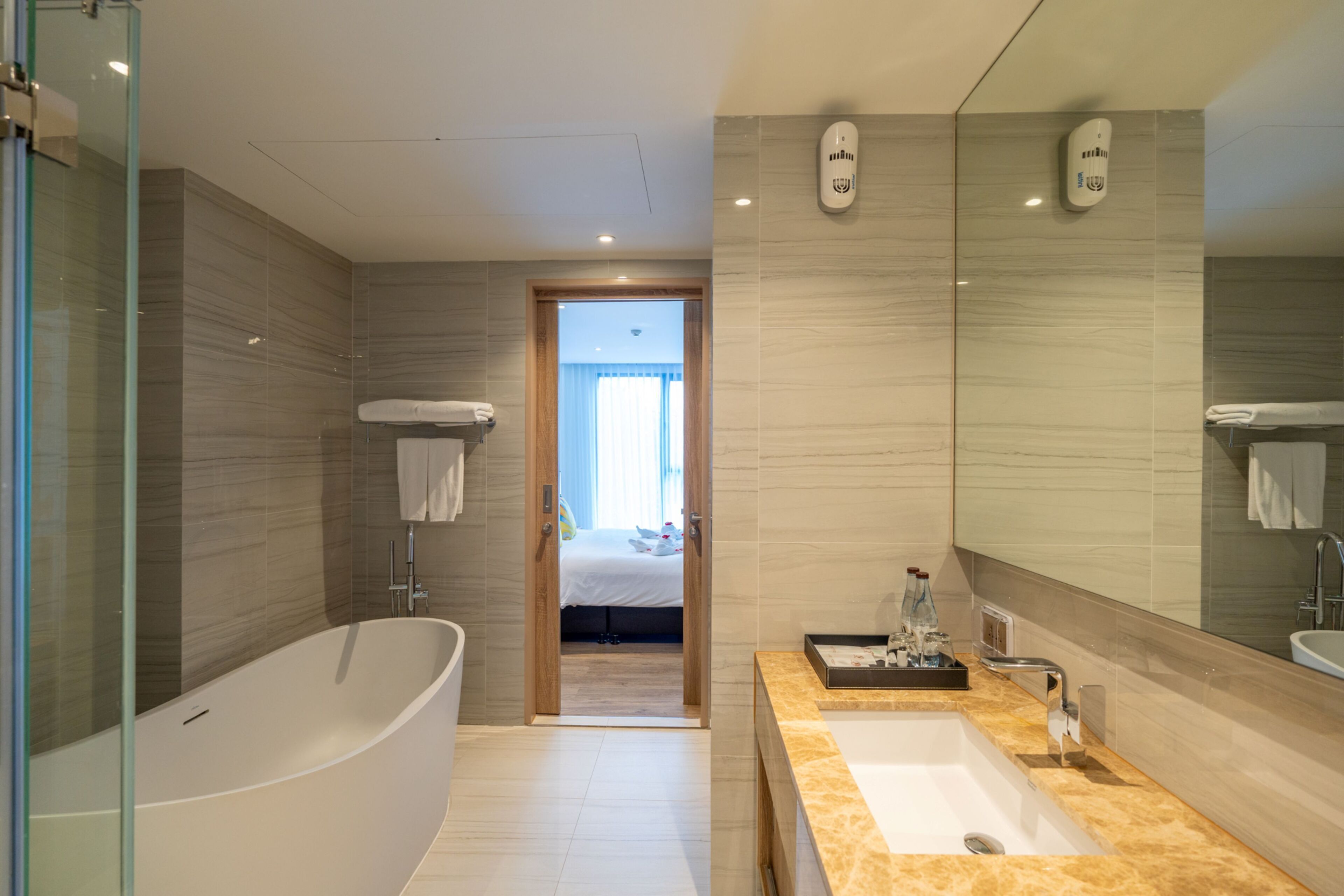 A modern bathroom with a freestanding bathtub, a large mirror, and a sink with a countertop.