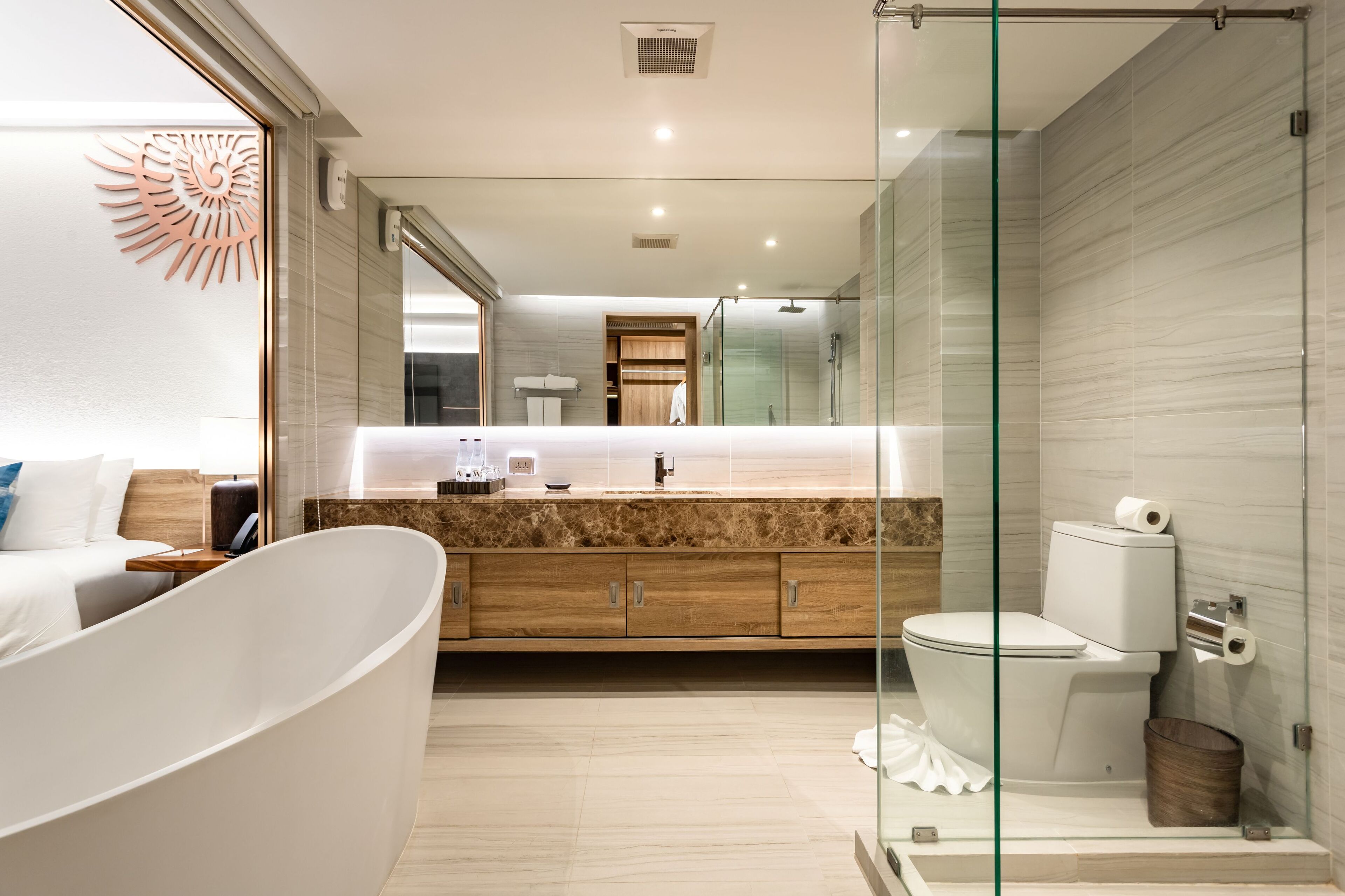 A modern bathroom with a freestanding bathtub, a glass shower enclosure, and a wooden vanity with a marble countertop.