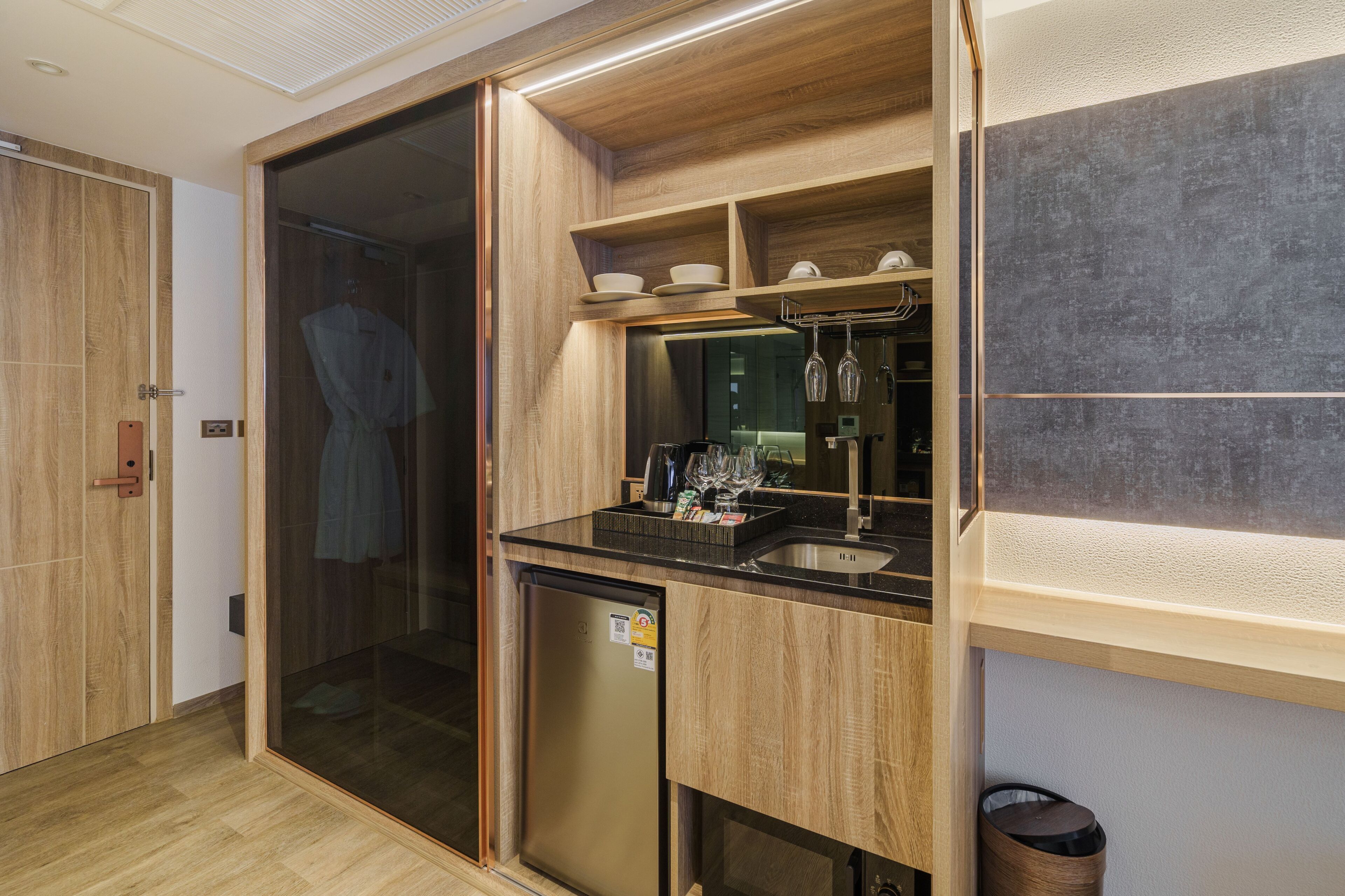 A modern bathroom with a glass shower enclosure, a built-in sink, and a small refrigerator.