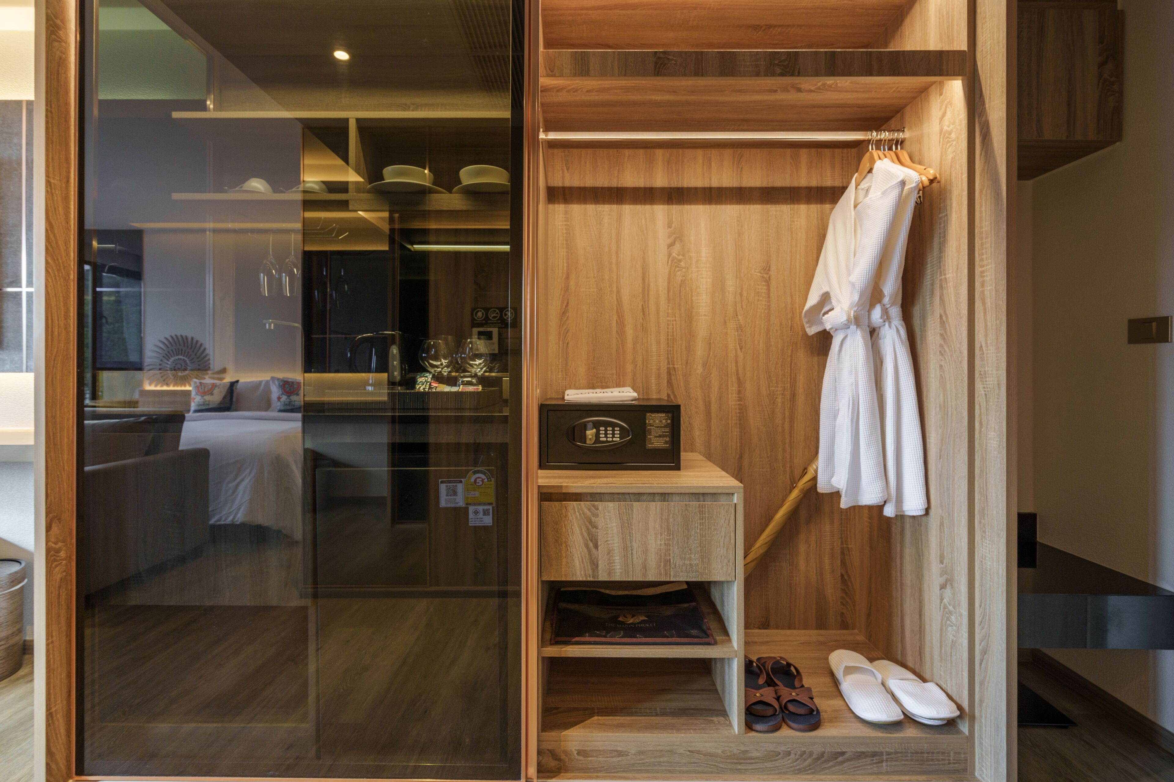 Un baño moderno con un mueble de tocador de madera, una bata colgada en un perchero y un par de zapatillas en el suelo.