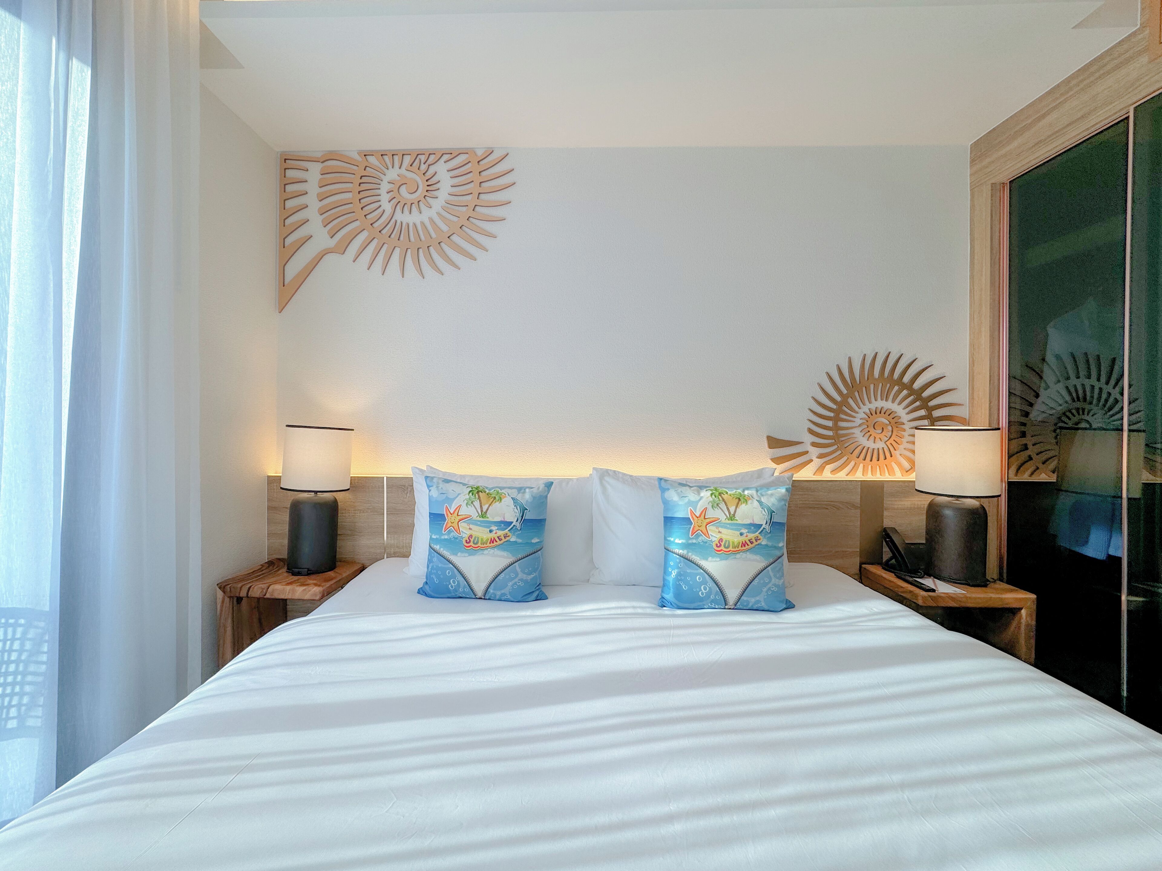 A hotel room with a large bed, two nightstands with lamps, and decorative wall art.