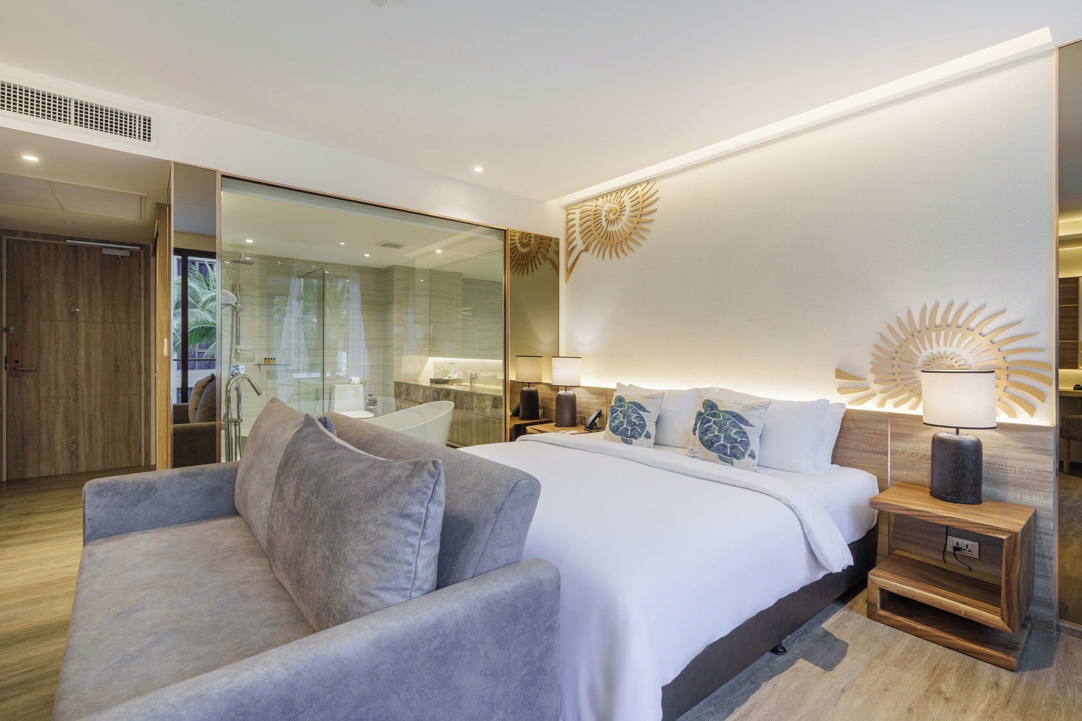 Une chambre moderne avec un grand lit, un canapé, une table de chevet en bois et une douche en verre.