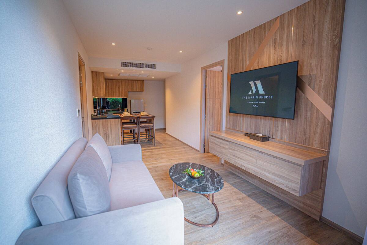 A modern living room with a sofa, a coffee table, and a TV mounted on a wooden wall.