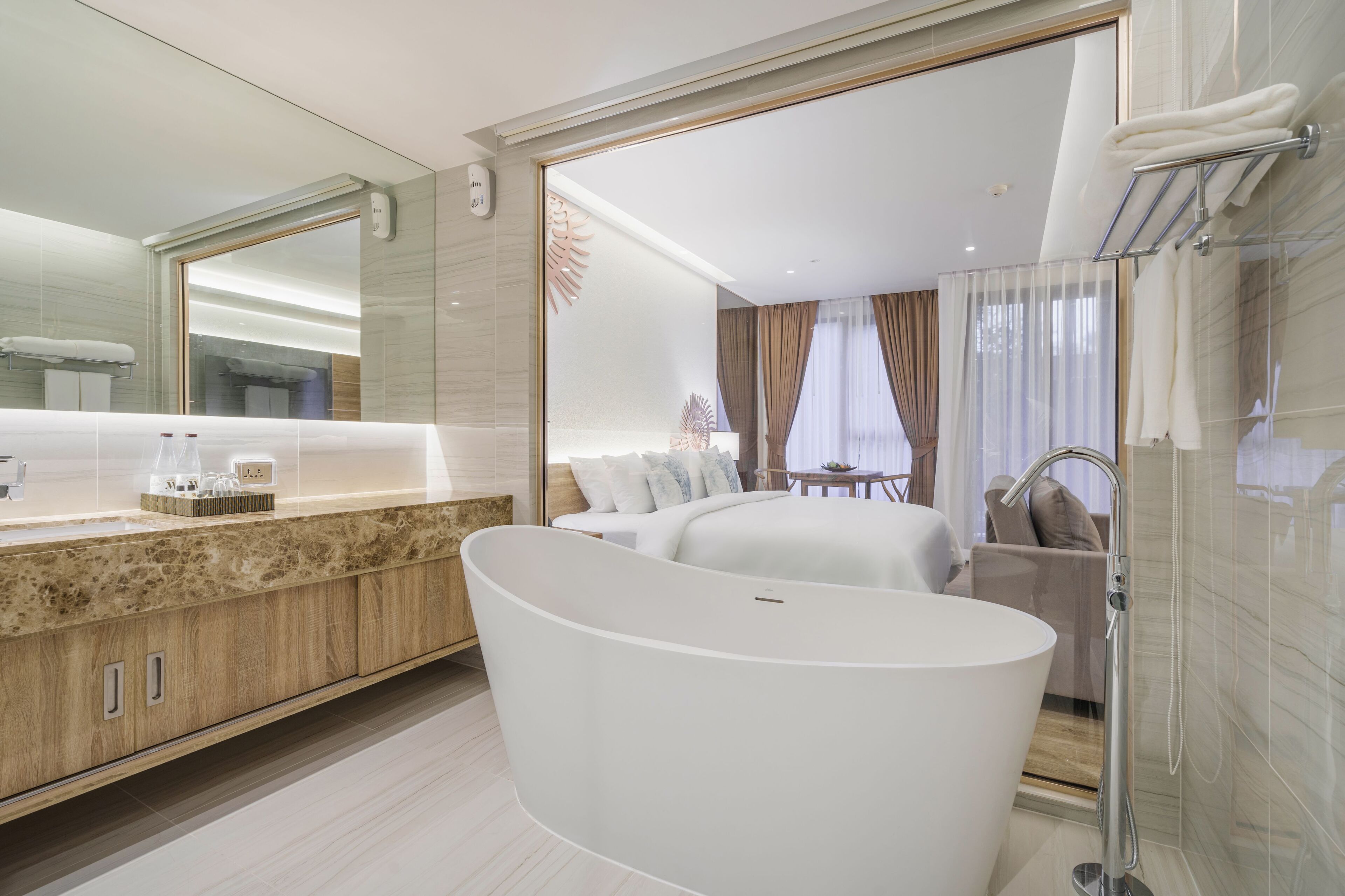 Une salle de bain moderne avec une baignoire sur pieds, un grand miroir et un meuble-lavabo doté d’un plan de travail en marbre.
