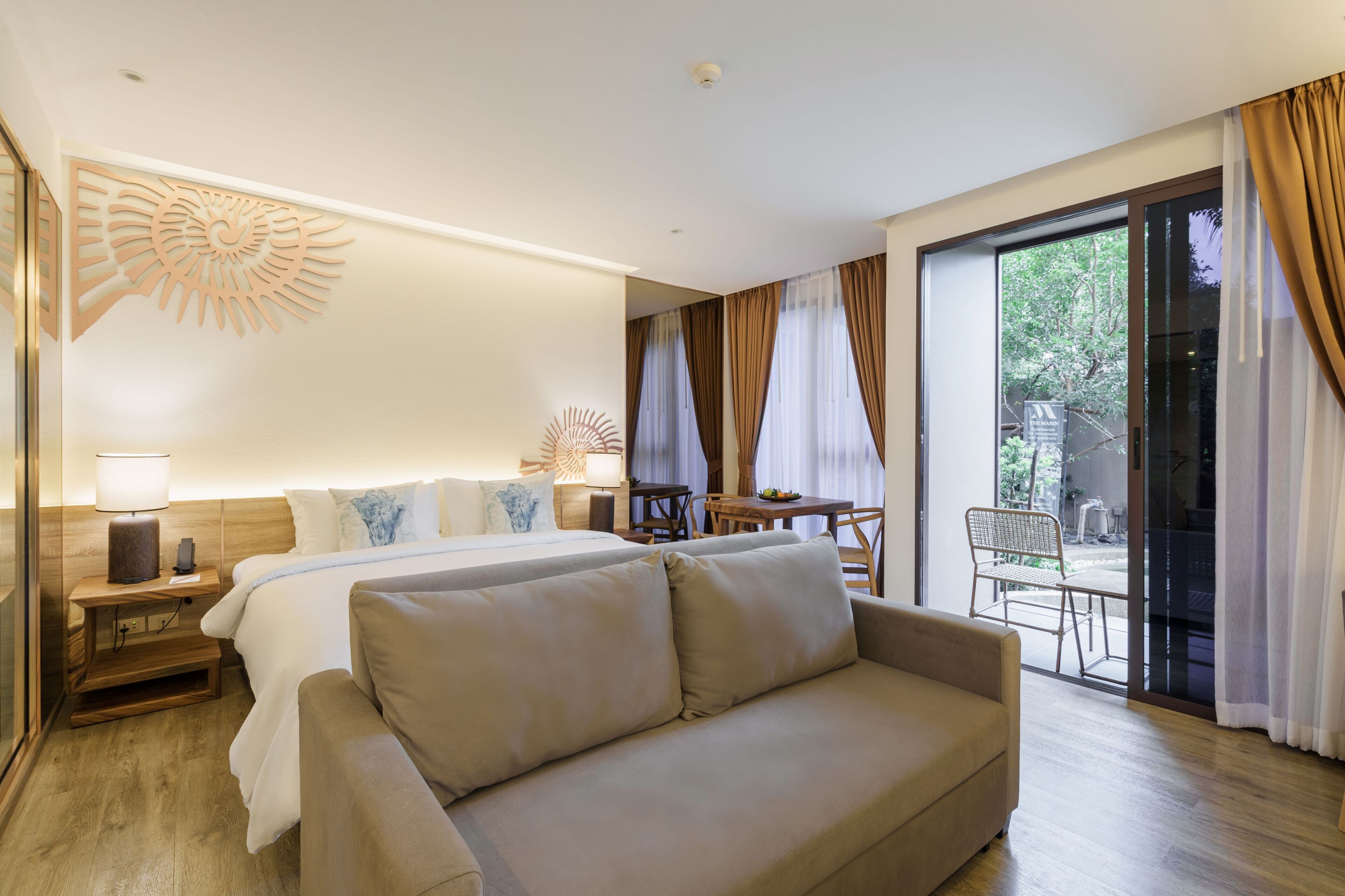 A hotel room with a bed, a sofa, a dining table, and a chair.