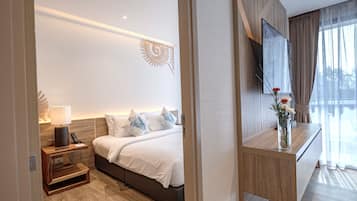 A modern hotel room with a bed, bedside table, lamp, and a TV on a wooden console.