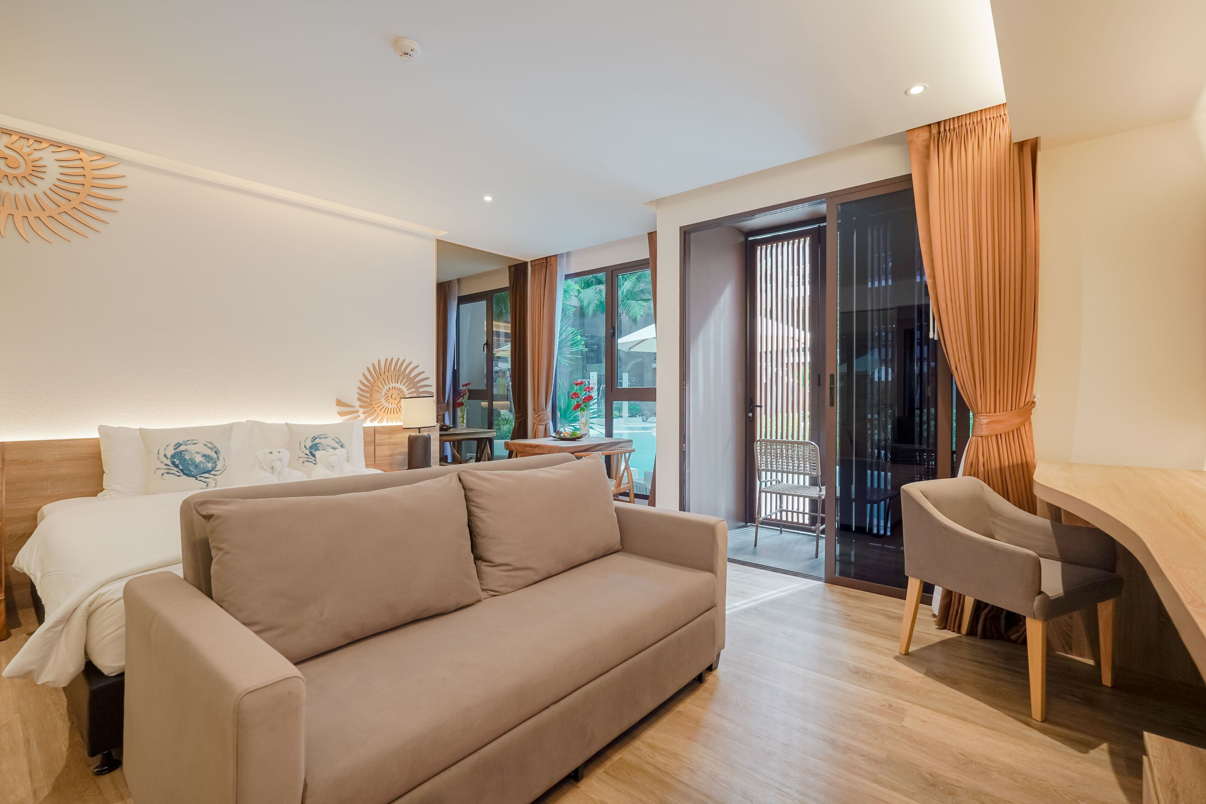 A modern hotel room with a sofa, a desk, and a view of the outdoors.